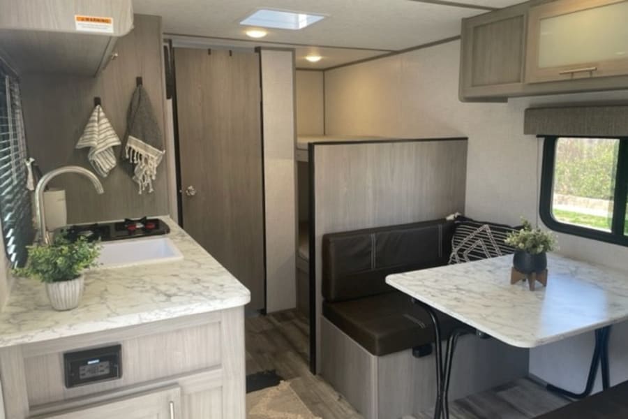 Cozy rv rental interior featuring a modern kitchen, dining area, and bunk beds for your travels.