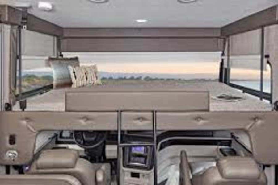 Spacious RV rental interior featuring a large cab-over bunk bed above the driver's cockpit. Perfect for family road trips.
