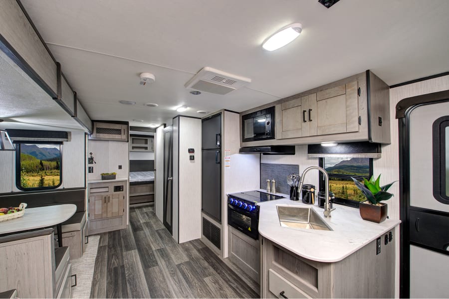 Spacious RV rental interior featuring a modern kitchen, dining booth, and scenic mountain views.