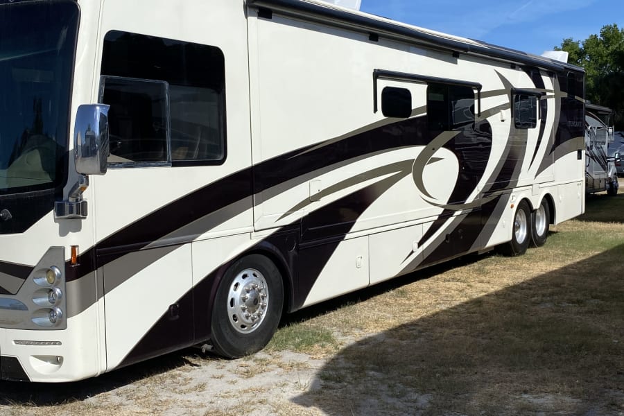 A spacious white and deep brown motorhome, featuring bold striped designs, is parked outdoors, ready for an rv rental journey.