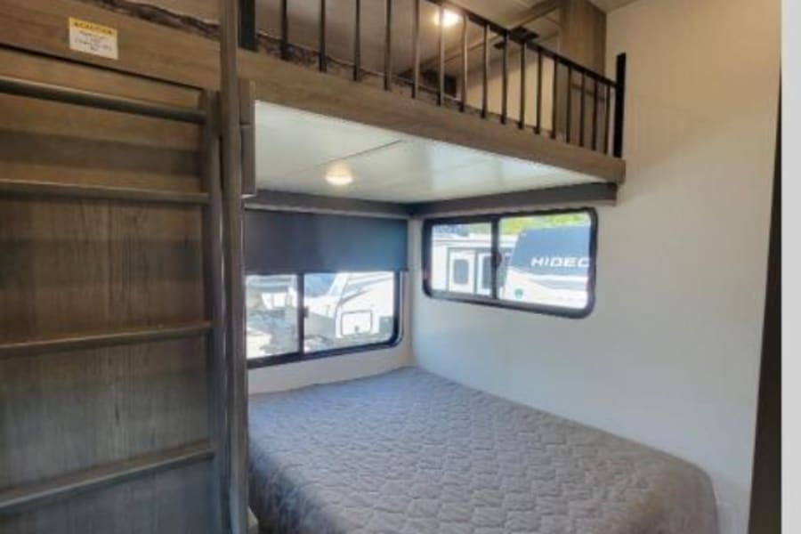 Experience the comfort of this RV rental, featuring a lower bed, ladder access to a loft, and large windows.