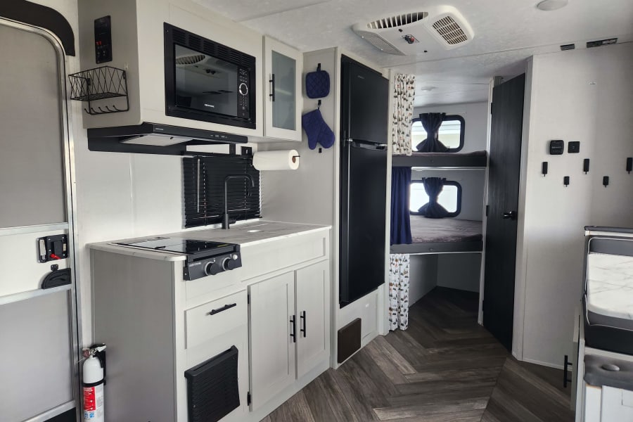 Experience a clean and modern rv rental interior, featuring a kitchen, bunk beds, and cozy living space.