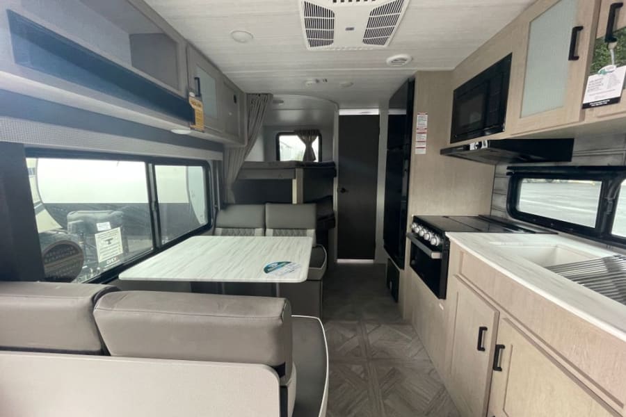 Spacious RV rental interior with modern kitchen, comfortable dinette, and bunk beds. Perfect for your next adventure!