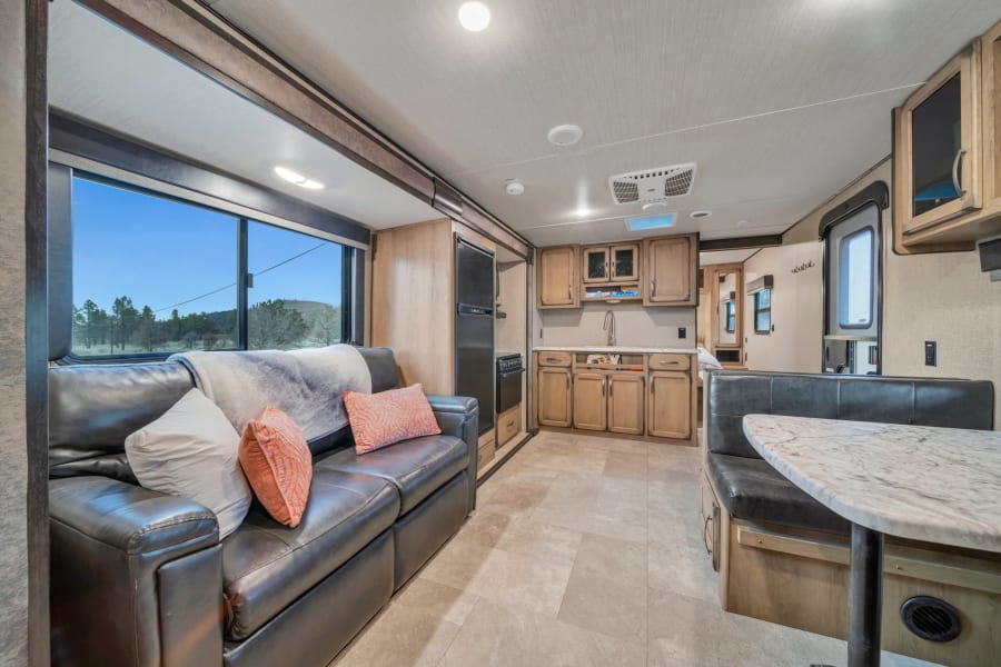 Spacious RV rental interior with living area, kitchen, and dining booth. Perfect for your next travel trailer adventure.