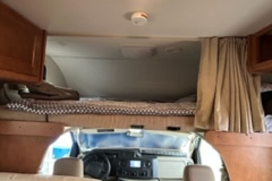 Explore this cozy RV rental interior! View from the main living area into the driver's cabin, featuring bunks,
