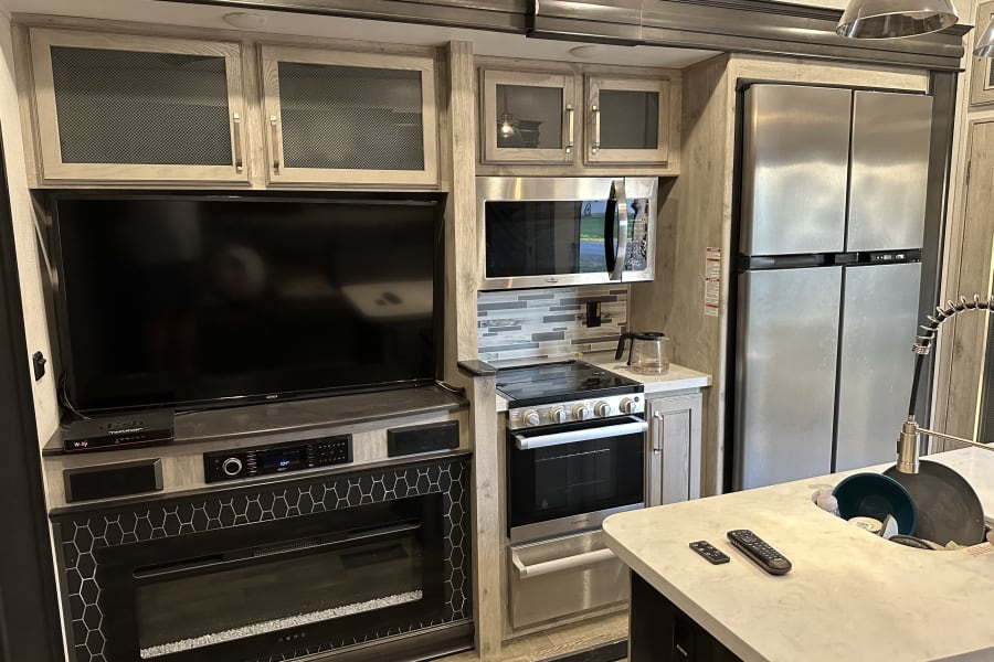 Modern RV rental interior: fully equipped kitchen, entertainment center, and sleek appliances.