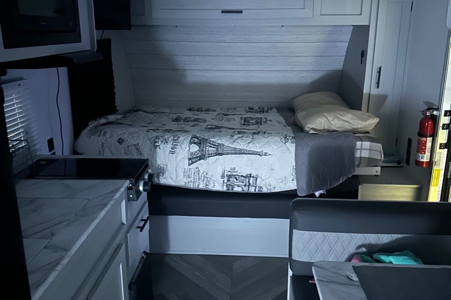 Modern RV rental interior with a cozy bed, compact kitchen, and dinette area. Perfect for your travels.