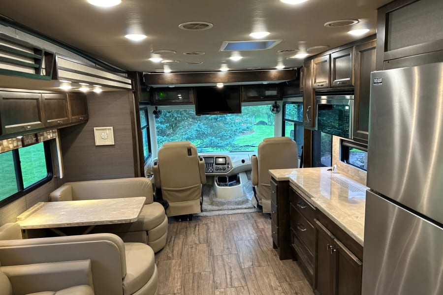 Explore this luxurious rv rental interior with living, dining, kitchen, and cockpit areas, ready for your next adventure.