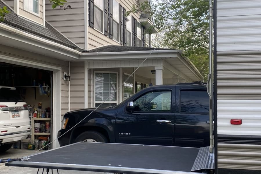 RV rental setup: A toy hauler with its rear ramp down in a driveway. Great for loading gear!