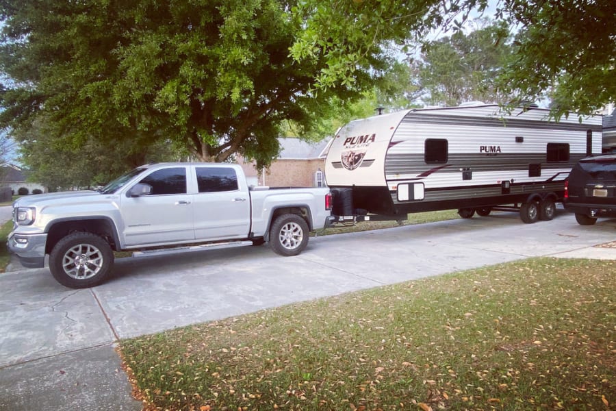 Silver pickup truck towing a Puma travel trailer RV rental, ready for your next adventure.