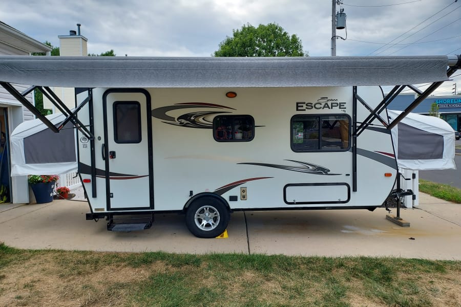 White Spree Escape pop-up RV rental with extended awning, parked on a driveway