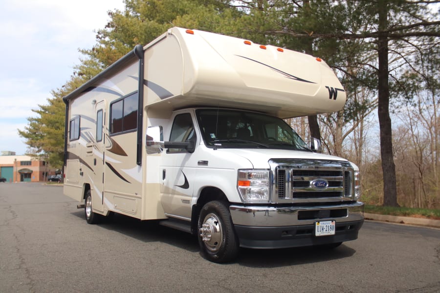 Bright tan Ford RV rental, a spacious Class C motorhome, parked on asphalt. Perfect for your next recreational journey.