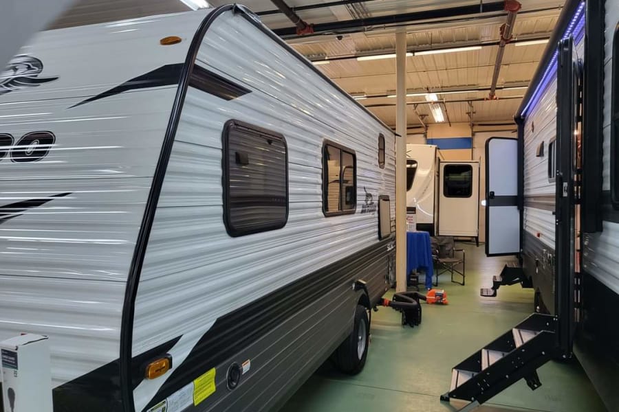 Inside an RV dealership: multiple travel trailers lined up for sale or rv rental. Perfect for your next road trip adventure!