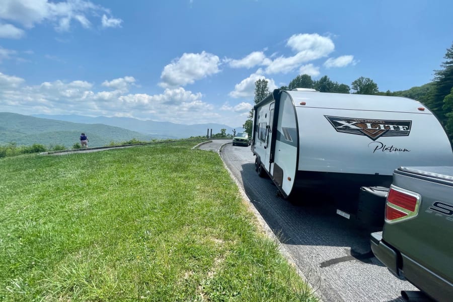 An RV rental and truck parked at a mountain scenic overlook, showing stunning panoramic views. Perfect for your road trip!