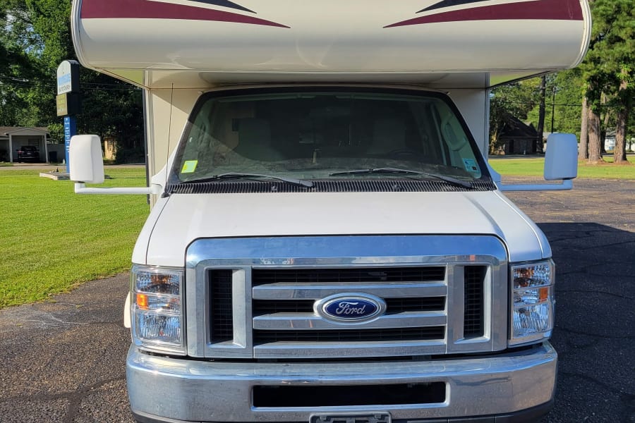 Front view of a white Coachmen Freelander RV rental on a Ford chassis, parked on pavement outdoors.