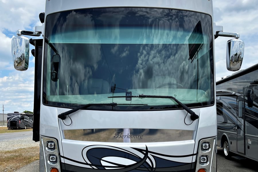 Front view of a white Berkshire motorhome, ideal for an RV rental adventure, reflecting cloudy skies.