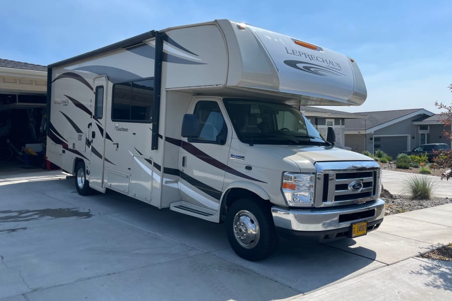 Bright Class C RV by Coachmen Leprechaun, an ideal rv rental option, parked on a residential driveway on a sunny day.