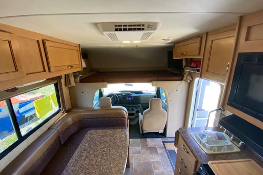 Spacious rv rental interior: full kitchen, dining area, over-cab bed & driver's cabin. Ready for your next adventure!