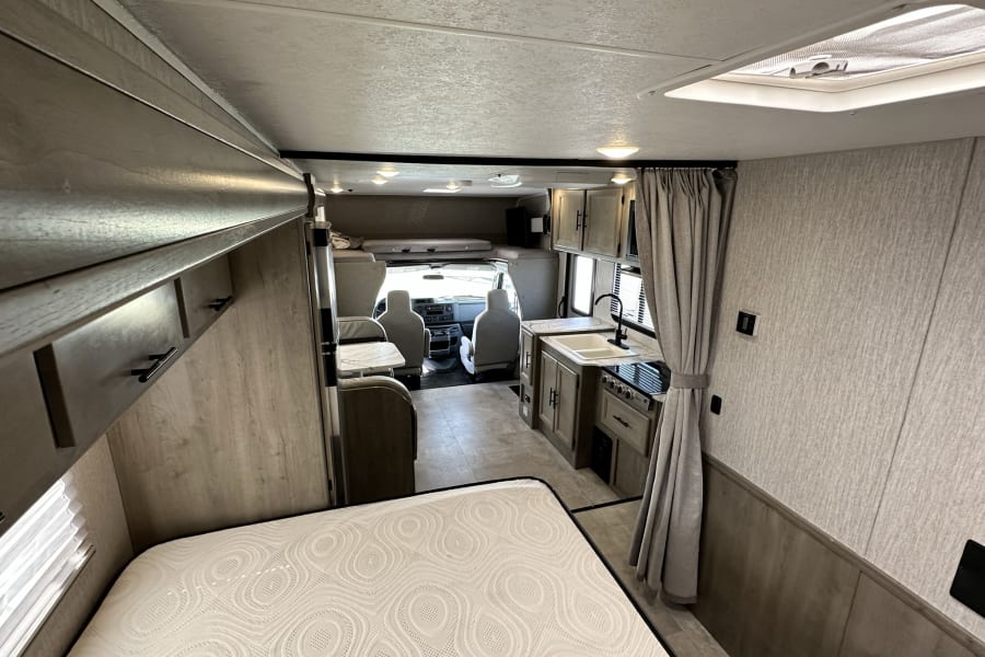 RV rental interior: A cozy motorhome with bedroom, kitchen, and driver's cab visible. Ready for travel adventures.