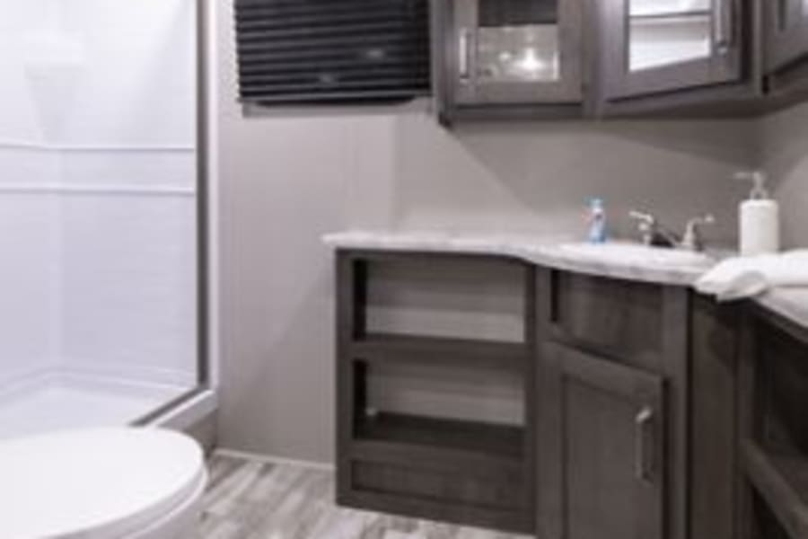 Spacious RV rental bathroom featuring a shower, toilet, and vanity with ample storage. Modern interior design for comfort.