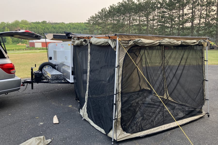 This rv rental setup features a compact travel trailer with an expansive screen room, perfect for outdoor camping comfort.