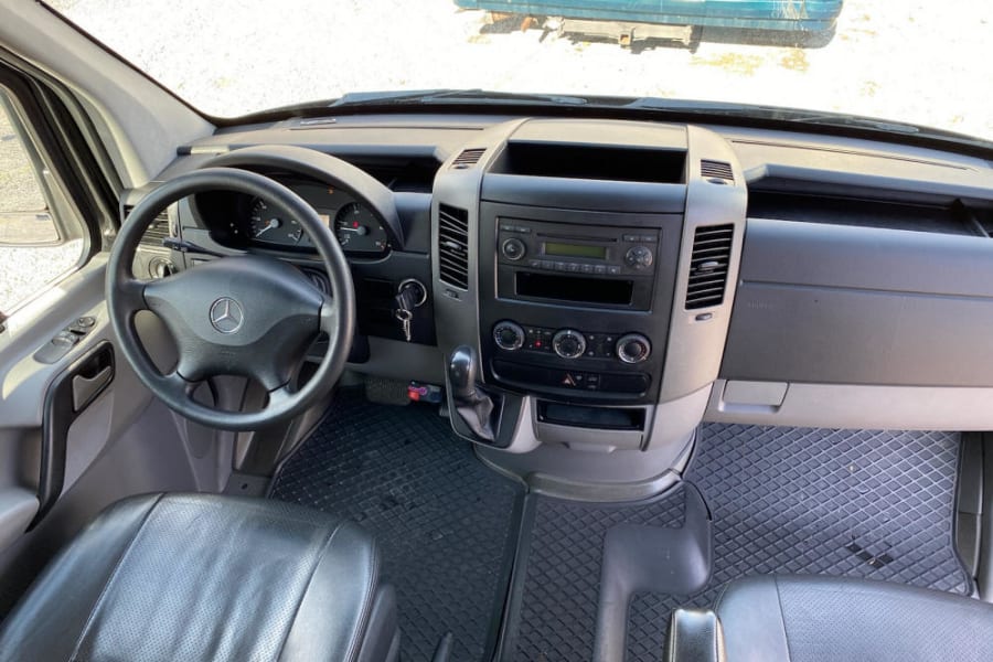 RV rental interior: Driver's view of the dashboard, steering wheel, radio, climate controls, and front seats.