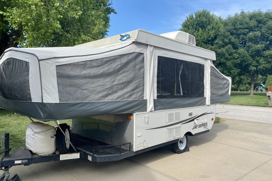 Grey pop-up RV rental (Jayco Jay Series) with AC, set up on a driveway for outdoor adventures.