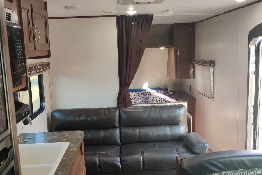 RV rental: Bright, modern interior featuring a kitchen, large leather sofa, dinette, and private sleeping area.