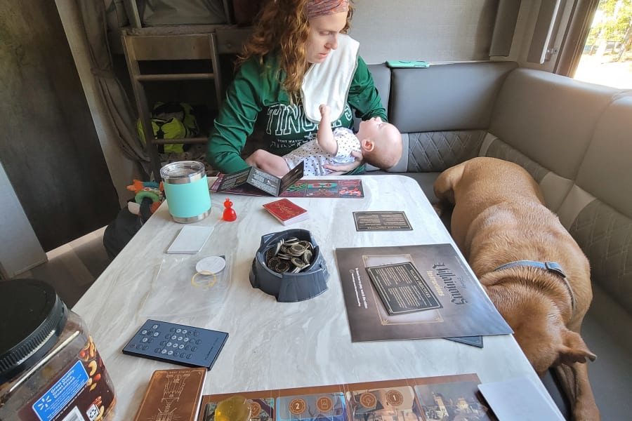 Family fun in an RV rental, with mom, baby, and dog enjoying a Disney Villainous board game.