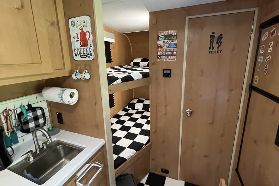This rv rental offers a compact kitchen, twin bunk beds, and a private toilet. Ideal for small group travel & camping.