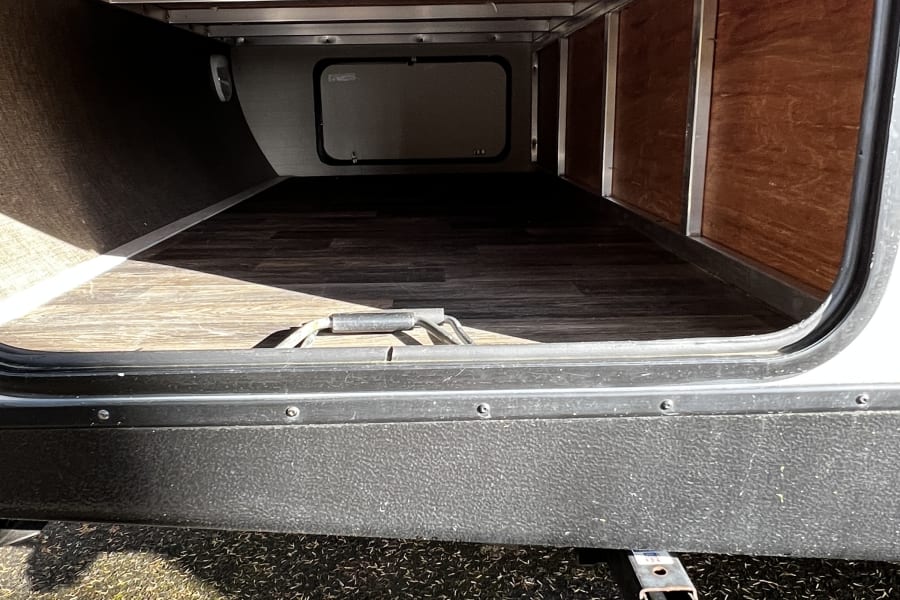 Explore the ample exterior storage of this RV rental. The large compartment features a clean, wood-look floor.
