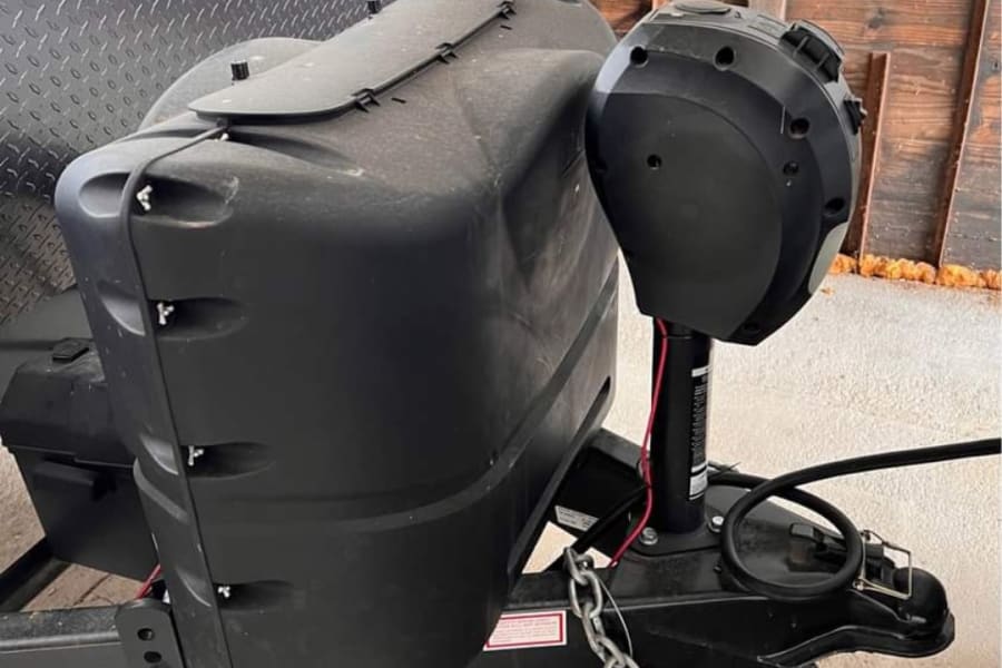 RV rental: Front of a travel trailer showing its black propane tank cover, power jack, and hitch for easy connection.