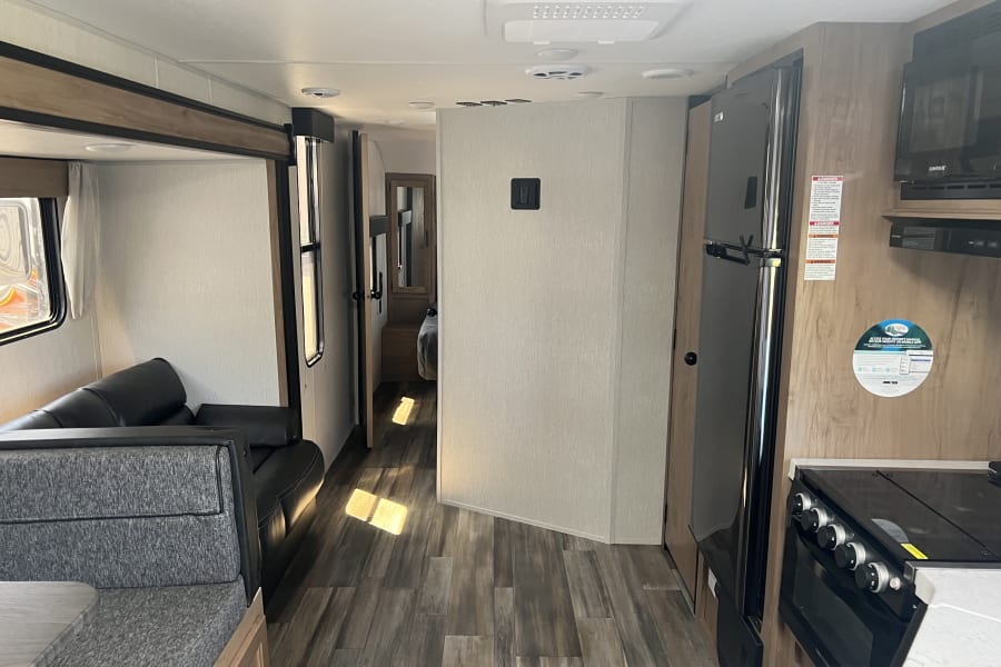 Spacious RV rental interior featuring a kitchen, dining area, sofa, and hallway leading to the bedroom.