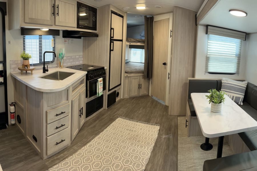 Bright RV rental interior featuring a full kitchen, dinette, and cozy bunk beds.