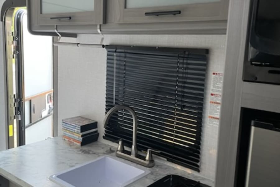 Compact rv rental kitchen: sink, two-burner stove, and overhead cabinets for cozy travel meals.