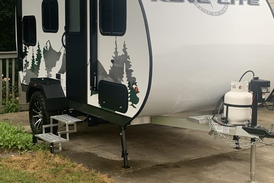 Experience outdoor adventure with this Rove Lite RV rental! A white teardrop travel trailer with cool mountain decals.