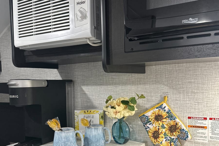 RV rental kitchen featuring a Haier AC, High Pointe microwave, Keurig, and cheerful sunflower decor, creating a cozy space.