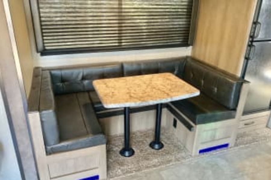 RV rental dinette with U-shaped booth seating and table. Enjoy meals and relaxation in your comfortable camper.