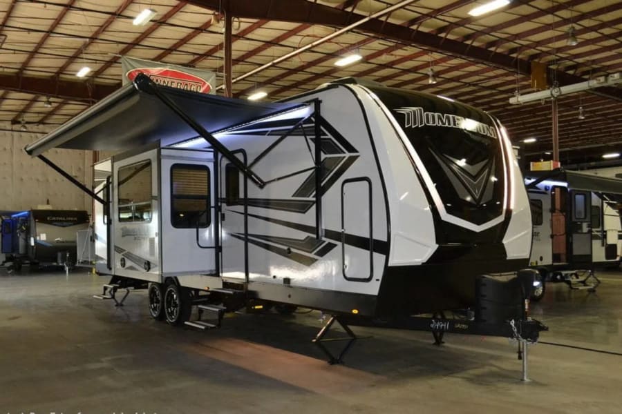 Spacious white and black travel trailer RV on display with awning extended, suitable for rv rental.