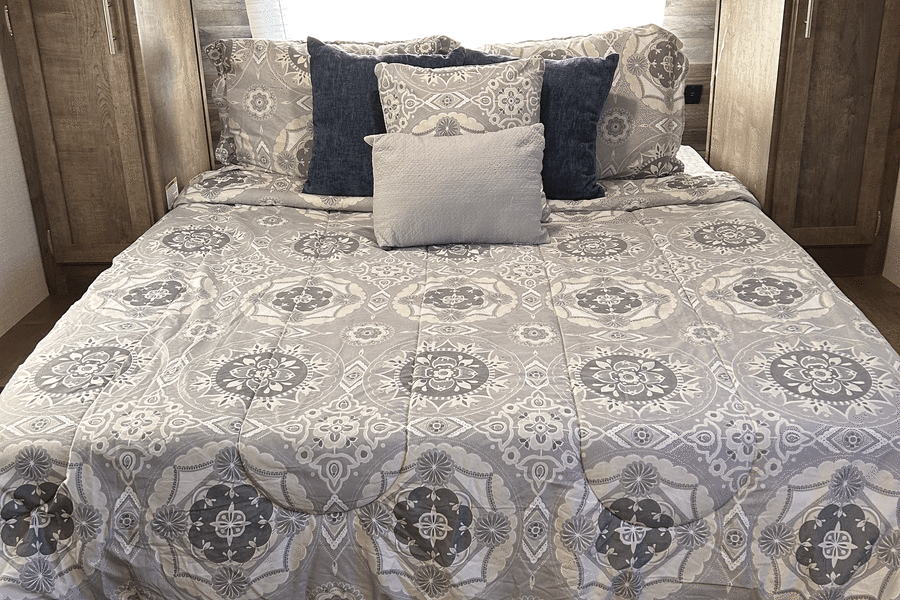 RV rental's cozy bedroom features patterned bedding, blue pillows, and warm wood interior.