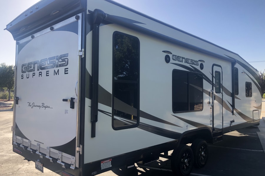 White & black Genesis Supreme toy hauler RV, "The Journey Begins...", perfect for your next rv rental adventure. Features a rear ramp.