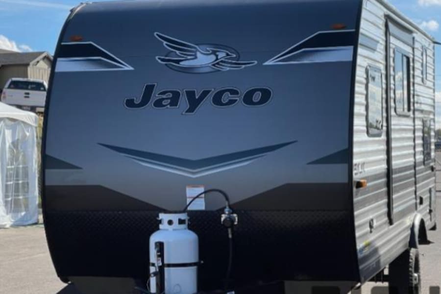 This gray Jayco travel trailer, featuring a front propane tank, is ready for your next rv rental adventure.