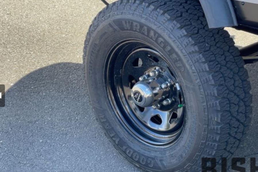 Close-up of a rugged Goodyear Wrangler tire & black wheel, perfect for your next rv rental trip.