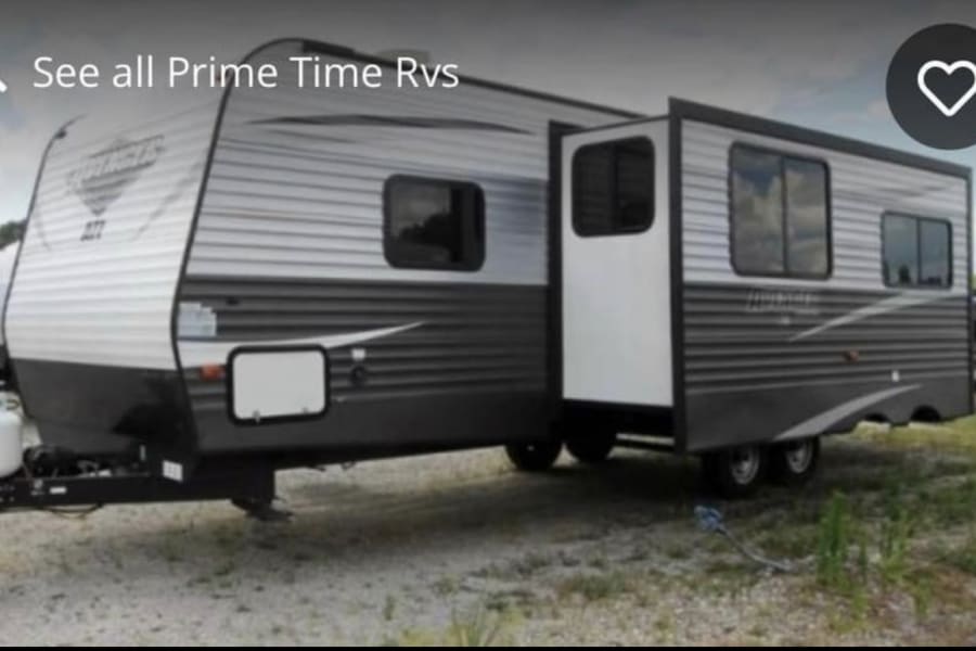 This large gray and white travel trailer RV rental features a side slide-out extended, enhancing its spacious interior.