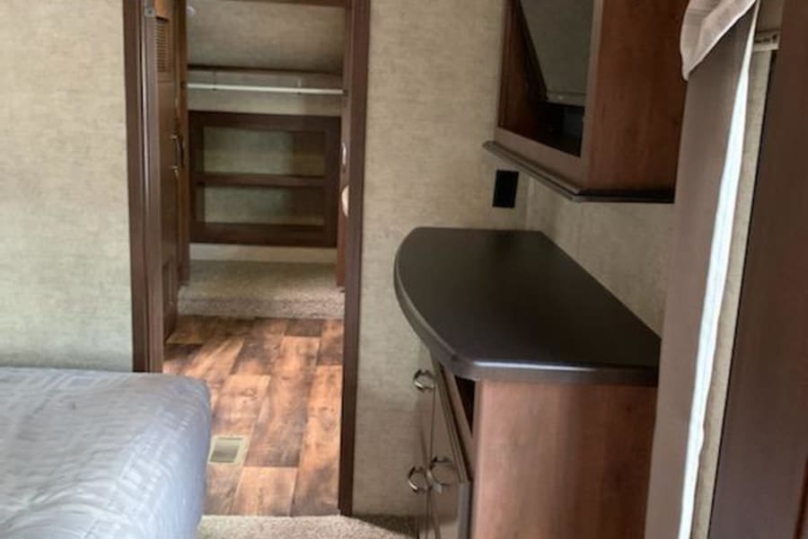 RV rental bedroom with a comfy bed, dresser, TV, and a view into the bunk room/storage area.
