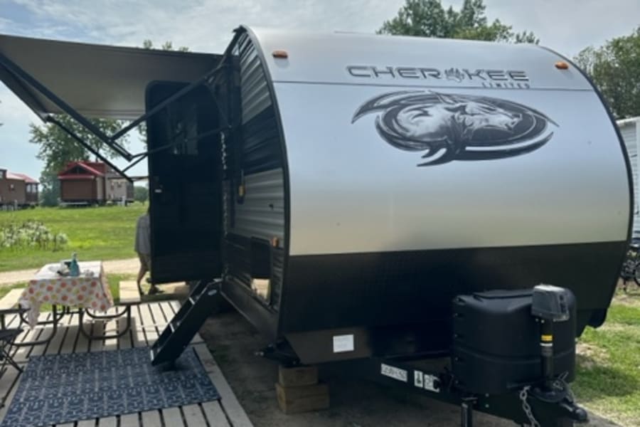 Cherokee travel trailer RV rental set up for camping, featuring an extended awning & outdoor patio.