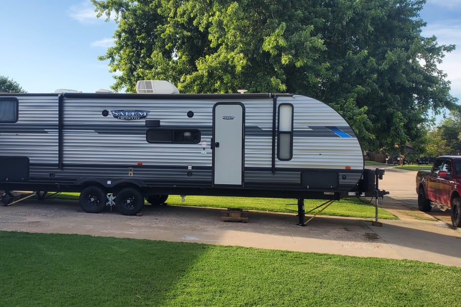 This Salem travel trailer (RV rental) is set up on a driveway with a red Ford truck nearby, ready for adventure.