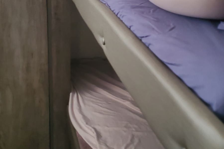 Cozy upper and lower bunk beds with bedding inside a modern RV rental.