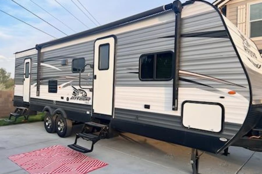 Modern gray & white travel trailer, ready for adventure! Steps down, awning extended. Explore with this RV rental.