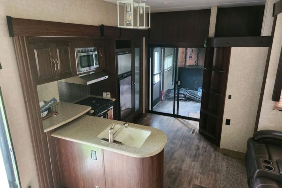 Spacious RV rental interior with a modern kitchen, comfortable living space, and rear toy hauler garage access.